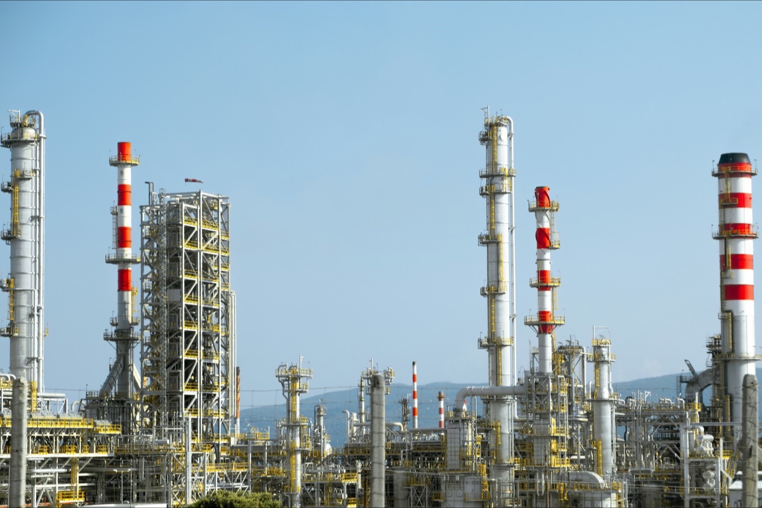 Wide view of a refinery exterior with columns and stacks under a blue sky